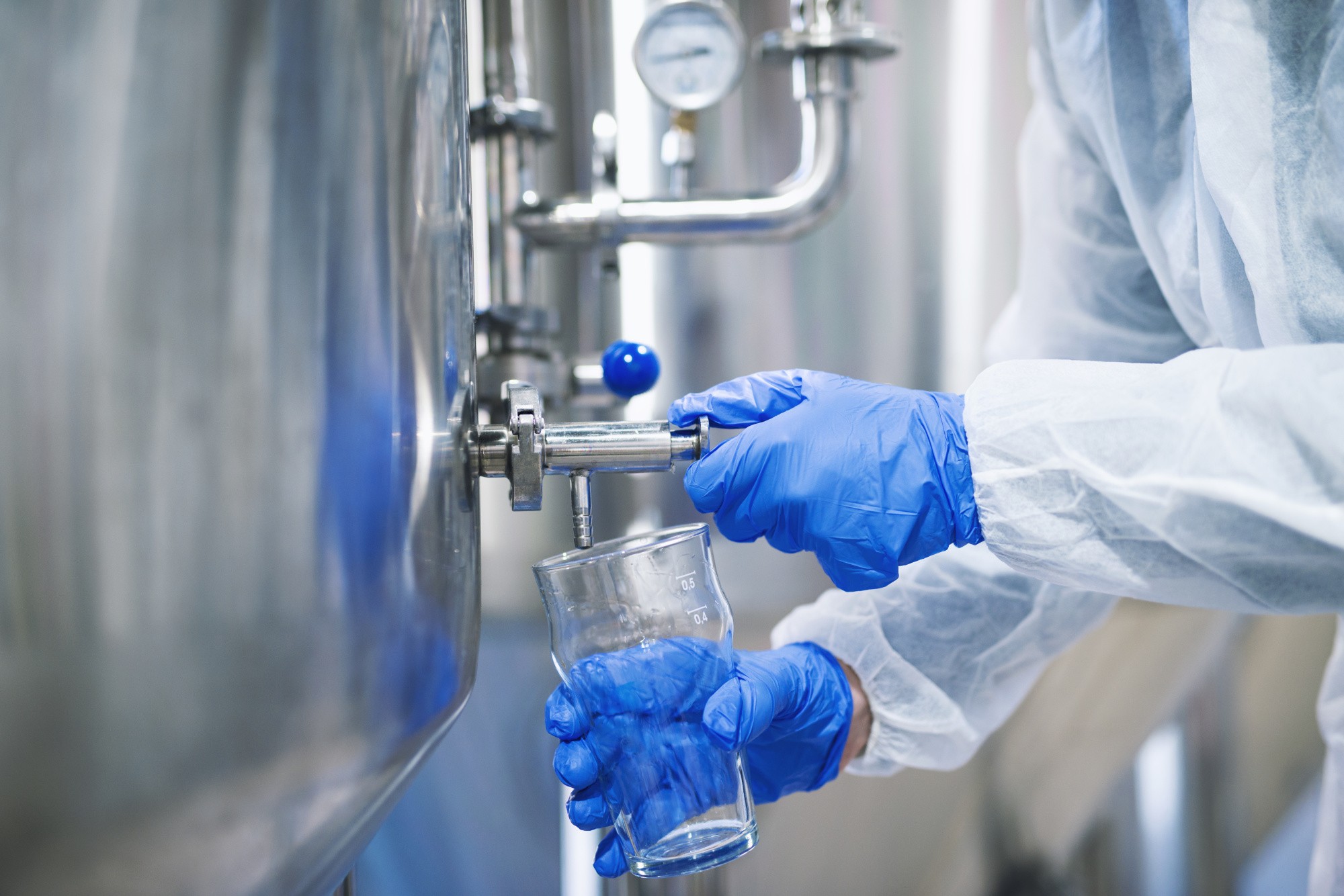 close-up-view-hands-protective-gloves-opening-tap-valve-filling-glass-with-samples-from-industrial-machine-reservoir.jpg