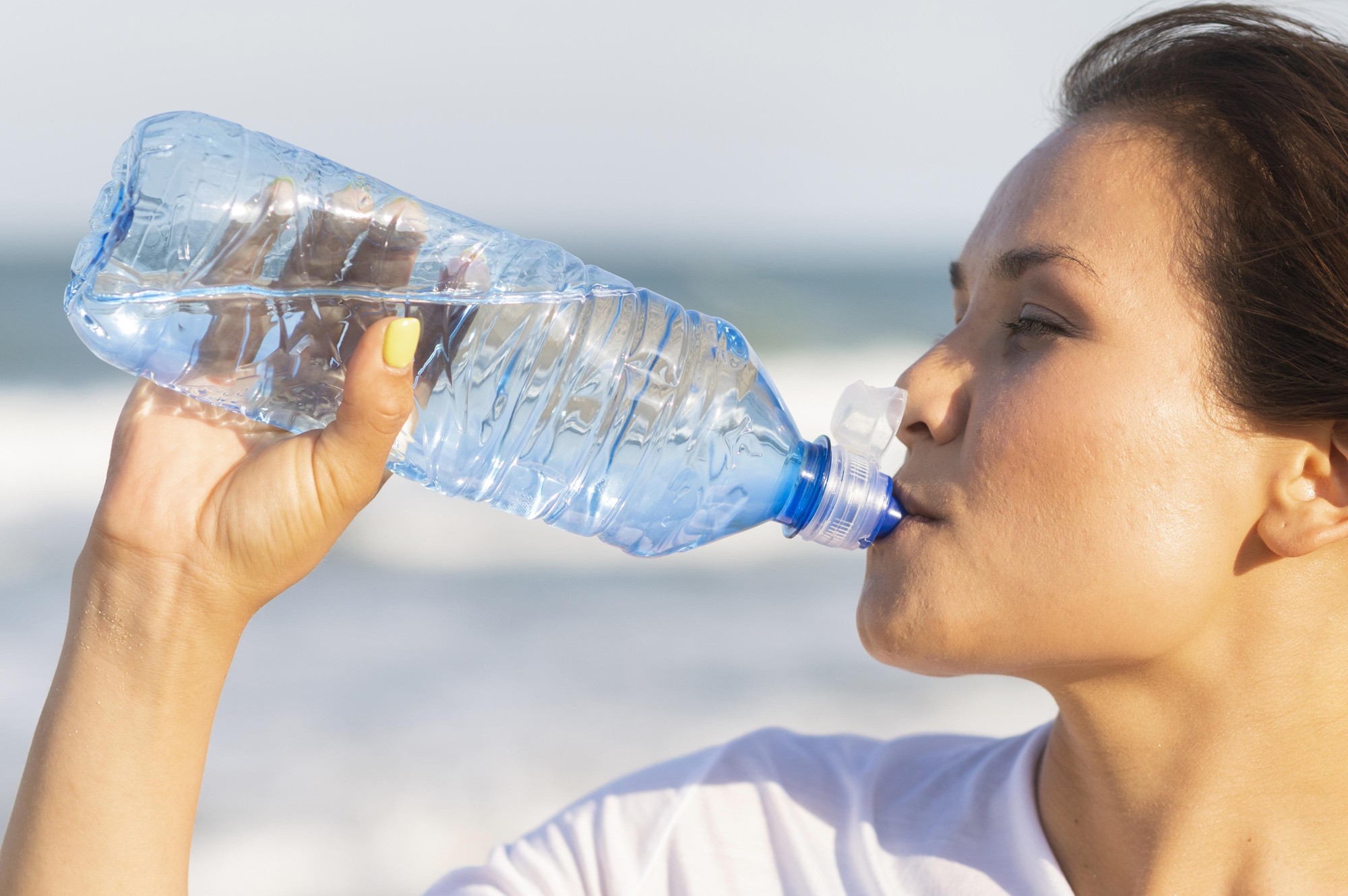 side-view-woman-drinking-water-beach-after-exercising.jpg