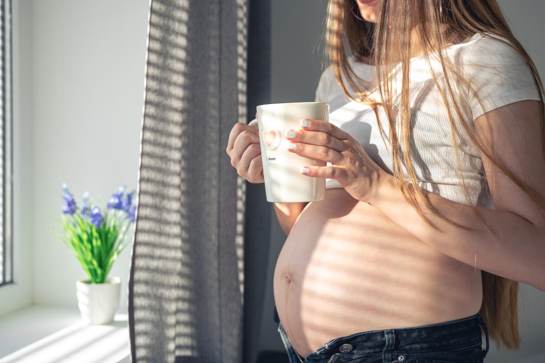 a-pregnant-woman-with-a-cup-of-tea-at-the-window-in-the-morning_169016-27469.jpg